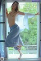 A naked woman standing in front of a window.