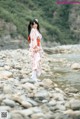 A woman in a pink kimono standing on a rocky beach.