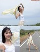 A woman standing on the side of a road next to the ocean.