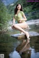 A woman sitting on a rock in the water.